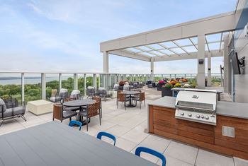 A patio with a grill and chairs overlooking a body of water.